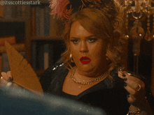 a woman with red lipstick looks at herself in a mirror with the hashtag itsscottiesstark