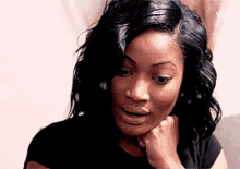 a woman with her hand on her chin is looking at the camera .