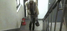 a woman in a fur coat is walking down stairs with a purse .