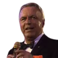 a man in a tuxedo is holding a microphone and smiling