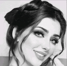 a black and white photo of a woman with braided hair and a bun smiling .