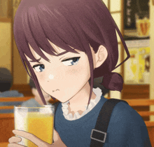 a girl is holding a glass of orange juice and making a face