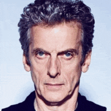 a man with gray hair and blue eyes looks at the camera