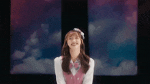 a young girl in a pink vest and bow tie is smiling .