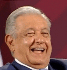 an older man is laughing with his eyes closed and his mouth open .