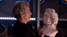 a man is touching a statue of a man 's face .