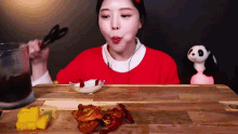 a woman in a red sweater is sitting at a table eating chicken