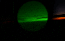 a green light is shining in the dark sky