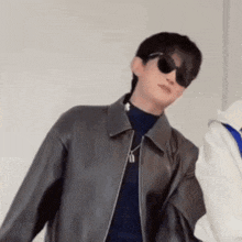 a man wearing sunglasses and a leather jacket .
