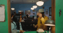 a man in a yellow jacket is giving money to a woman in a blue shirt