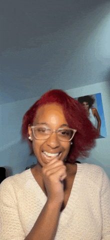 a woman with red hair is wearing glasses and a white shirt