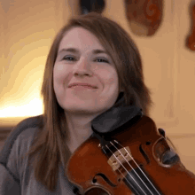 a woman is smiling while holding a violin in her hands