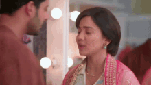 a man and a woman are looking at each other in front of a mirror .