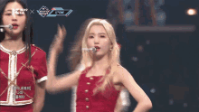 a woman in a red dress is singing into a microphone while another woman looks on ..
