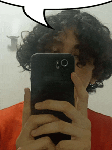 a person with curly hair taking a selfie with a speech bubble above them