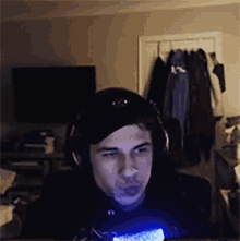 a man wearing headphones and a hat is playing a video game in a dark room