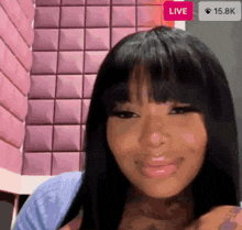 a woman is sitting in front of a pink wall and smiling .