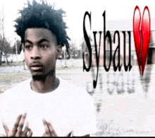 a young man in a white shirt is standing in front of a building with a broken heart in the background .