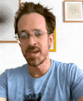 a man wearing glasses and a blue t-shirt with a picture of a building on it