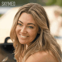 a woman is smiling in front of a skymed sign