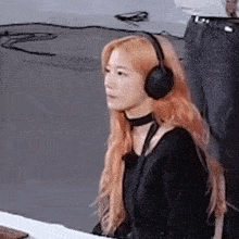 a woman wearing headphones and a choker is sitting on the floor .