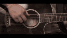 a person playing an acoustic guitar with a reflection of a person behind it