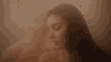 a woman is taking a shower through a window with water drops on it .