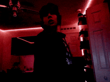 a person standing in a dark room with a red light behind them and a hoodie that says ' suicide squad '