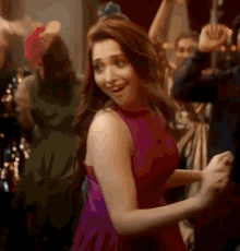 a woman in a pink dress is dancing at a party with a group of people .