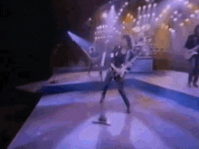 a man is playing a guitar on a stage with other people .