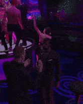a man in a suit stands in front of a group of people dancing on a stage