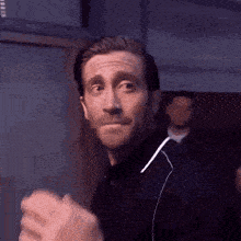 a man with a beard is making a funny face while wearing ear buds .