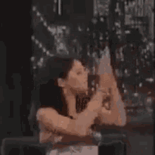 a woman in a strapless dress is holding a candle in her hand and looking at the camera .