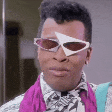 a man wearing a pair of sunglasses with a triangle on the lens is making a funny face .