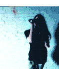a woman is singing into a microphone in front of a white brick wall