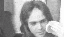 a man with long hair is cleaning his face with a cotton swab .