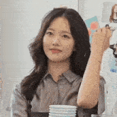 a woman in a grey shirt is sitting at a table with a cup of coffee in front of her .