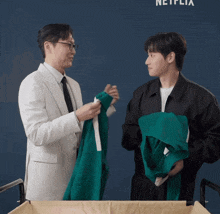 two men standing next to each other in front of a netflix sign