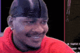 a man wearing a red hoodie and a black headband smiles for the camera