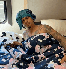 a man with a tattoo on his chest is laying in bed with a unicorn blanket
