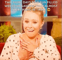 a woman is smiling and holding her chest while sitting on a chair .