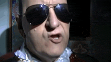 a man wearing sunglasses and a white shirt makes a funny face
