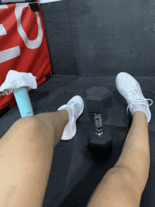 a person 's legs are on a mat next to a dumbbell and a bottle that says ' fitness '