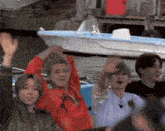 a group of young men sitting on a boat with their hands in the air