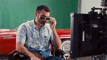a man wearing sunglasses is sitting in front of a monitor