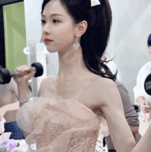 a woman in a strapless dress is holding a dumbbell in her hand