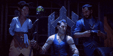 a man in a blue vest is sitting on a throne surrounded by other people