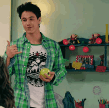 a man in a green plaid shirt holds an apple
