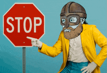 a man in a yellow jacket is pointing at a stop sign