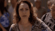 a woman in a snake print shirt is making a funny face in a crowd .